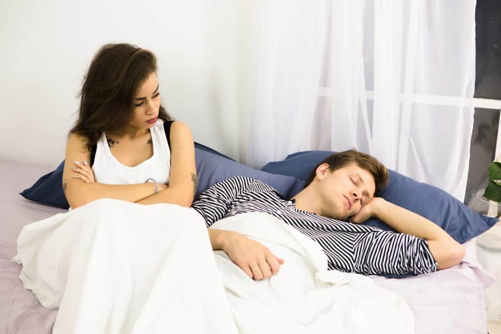 Disappointed Woman In Bed With A Man Sleeping