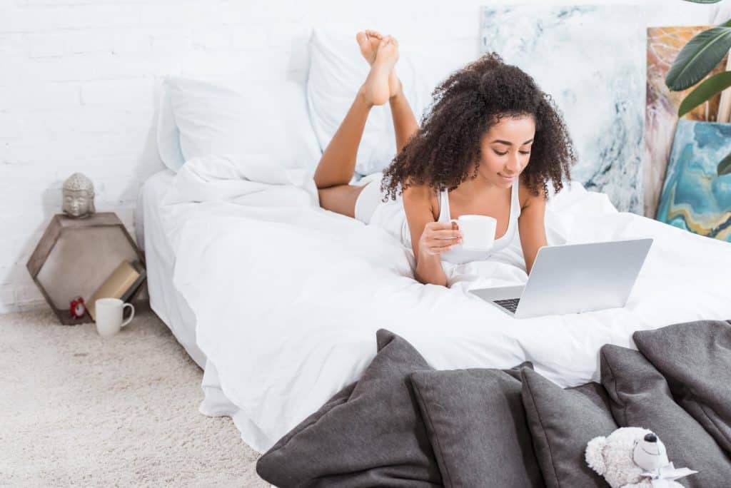 Woman In Bed Chatting On Her Laptop