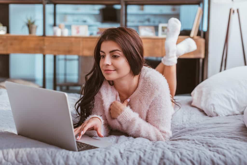 Woman In Bed Using Her Laptop